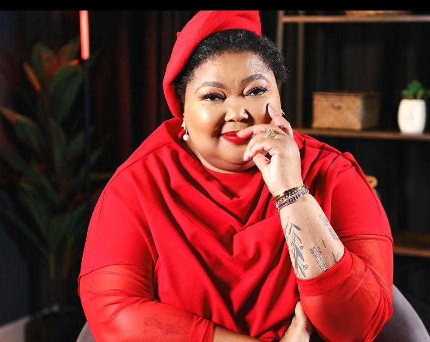 Dr Tlaleng Mofokeng, seated in a red ensemble, looking toward the camera with her chin resting on her hand.